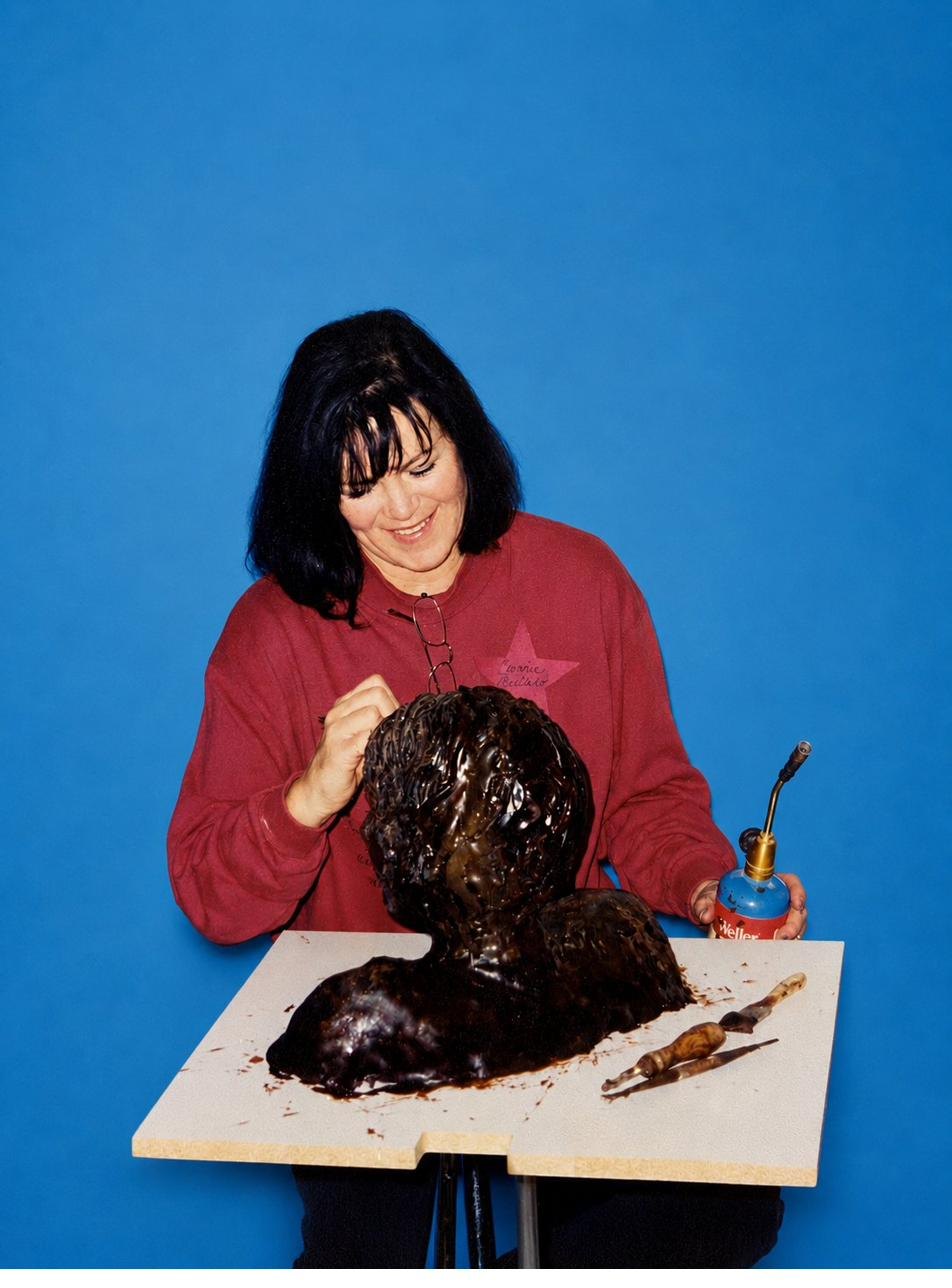 Cathe Bloomfield Collard smiling as she models a wax sculpture in her studio